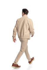Naklejka premium young fashion man in beige jacket looking to side and stepping