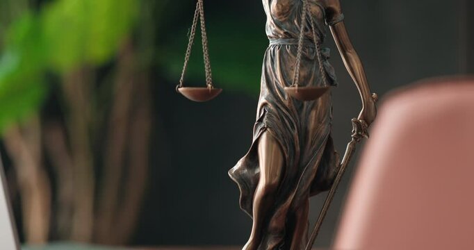 Lawyer's office. Statue of justice with scales and a laptop in a modern office cubicle. Concept of legal law, counseling and concept of justice.