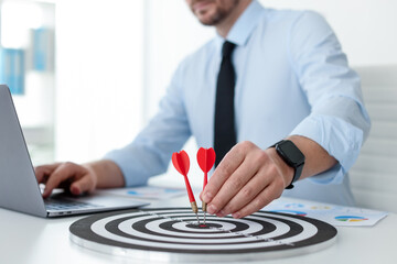 Man with dart aiming at dartboard while working indoors, closeup