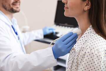 Sonographer conducting ultrasound examination of woman's thyroid gland in clinic, closeup