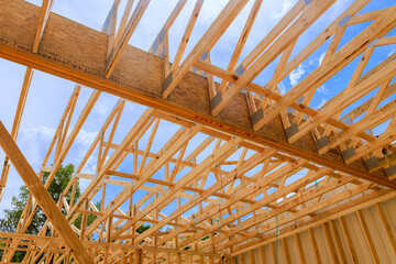 Workers are assembling wooden trusses beams for new house under clear sky.