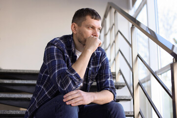 Depressed man sitting on stairs in building