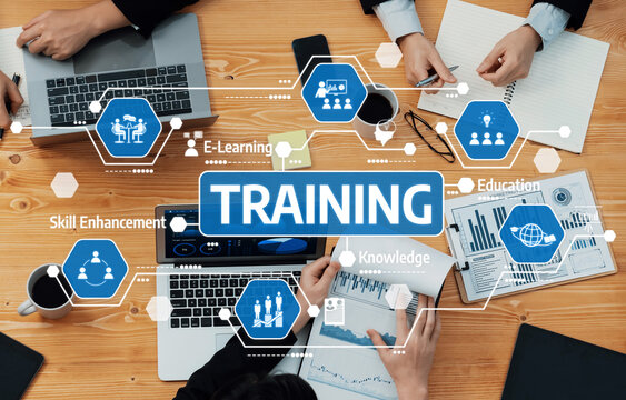 This image depicts a collaborative training session with multiple professionals engaged in discussions, featuring laptops, notes, and dynamic learning materials in a modern workspace. Amity