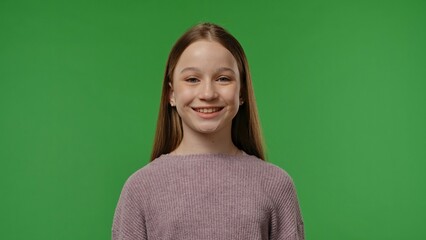 Fototapeta premium Teenage girl posing at camera smiling, positive expression, isolated on chroma key green screen studio background mockup.