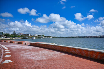 View of the Tejo River from the red-paved promenade in Seixal, Portugal, with cloudy sky on a...