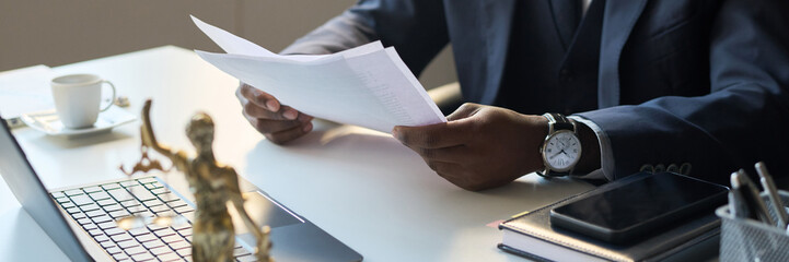 High angle view of unrecognizable Black male legal attorney working in office, looking through...