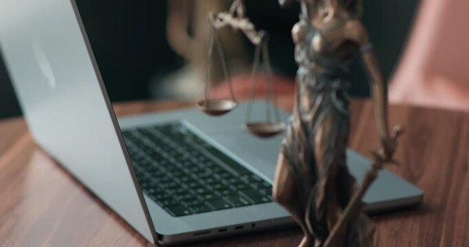 Lawyer's office. Statue of justice with scales and a laptop in a modern office cubicle. Concept of legal law, counseling and concept of justice.
