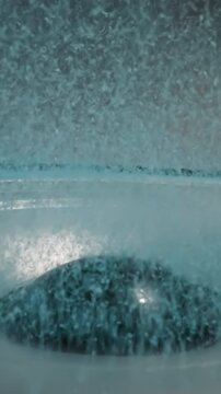 Blue sand for aquarium lies on edge of loudspeaker diaphragm and flows from movement to dust cap in center. Small granules moves on electrodynamic speaker driver macro