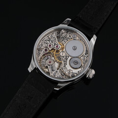 Close-up view of vintage mechanical wristwatch movement with visible gears, golden bridges, and...