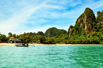 Railay Beach, Krabi Province, Thailand, 10 July 2023 : the beautiful seascape of sand beach, blue sky, sea and limestone mountains at seashore. Motor boats on turquoise waters. picture perfect hot day