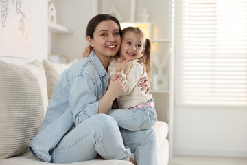 Obraz premium Happy mother with her cute little daughter on sofa at home. Space for text