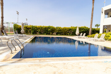 Summer seaside relax mood travel vacation a luxurious pool hotel interior for a summer holiday in warm countries. Beautiful tropical beach hotel resort with swimming pool, sun loungers palm trees