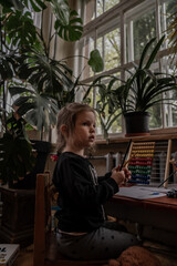 Small little girl with long hair playing in children corner in an restaurant with beautiful and green interior