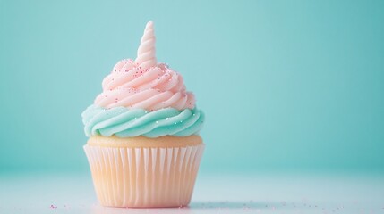 Whimsical unicorn cupcake with pastel swirled frosting and sugar horn on teal background