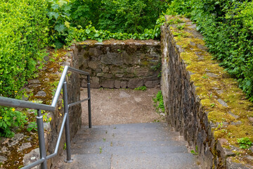 Curved stone steps lead to a lush green pathway nestled in nature's embrace on a tranquil day
