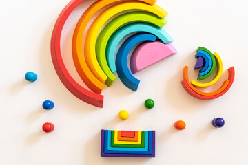 Colorful wooden rainbow shapes arranged in playful design with vibrant colors and various geometric forms on a light surface
