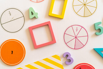 Educational learning tools arranged on a surface with colorful shapes, numbers, and fraction circles for interactive math activities with children. education,  back to school