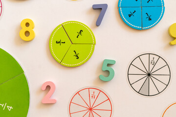 Colorful learning tools for teaching fractions and numbers displayed on a white background in a classroom setting