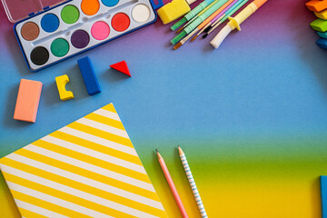 Colorful art supplies arranged on a vibrant backdrop with paint, crayons, and sketchbook ready for creativity at a craft table