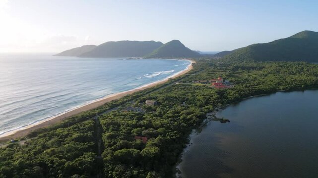 Vista a&eacute;rea de drone da Praia da Arma&ccedil;&atilde;o e da Lagoa do Peri, localizadas no Campeche, sul da Ilha de Florian&oacute;polis, Brasil. Paisagem litor&acirc;nea e natural c&ecirc;nica.