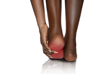 Black Female African woman standing feeling pain in her foot , female suffering from feet ache and using  hand to  massage in other to relax muscle 

