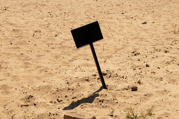 An empty sign sticks out on the sand on the bank of the Dnieper River in Ukraine, space for text