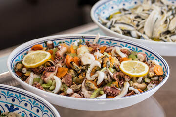 Insalata di Mare, Italian Seafood Salad in a ceramic plate. Italy's classic light, bright salad of gently cooked and marinated seafood with lemon juice, olive oil, parsley, and subtle spices