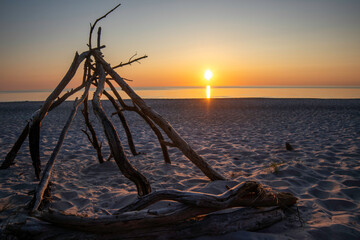 Stunning sunset over the Baltic Sea illuminating the Darß Peninsula coastline with a unique driftwood structure