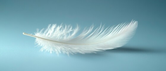 Obraz premium White feather rests gently on pale surface, creating serene atmosphere with delicate texture.