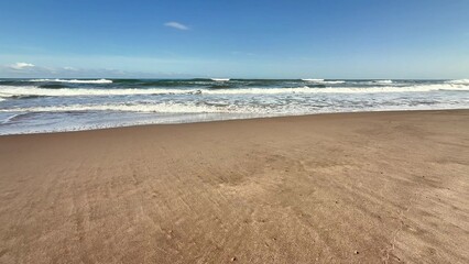 Fototapeta premium A Serene Beach Landscape Featuring Gentle Waves Lapping Against the Shore and a Clear Blue Sky