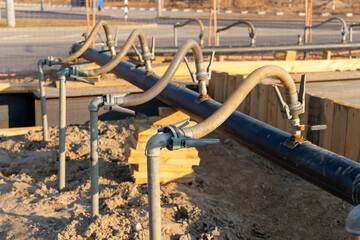 A close-up view of a series of flexible hoses connected to a pipe at a construction site