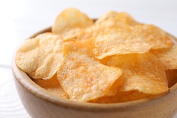 Tasty potato chips in bowl on white table, closeup
