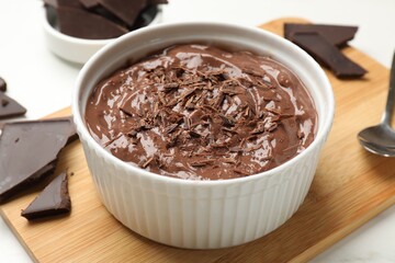 Tasty chocolate pudding in bowl served on white table, closeup