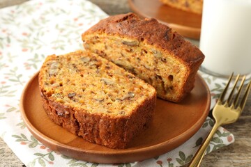 Pieces of homemade carrot cake with nuts and fork on wooden table, closeup