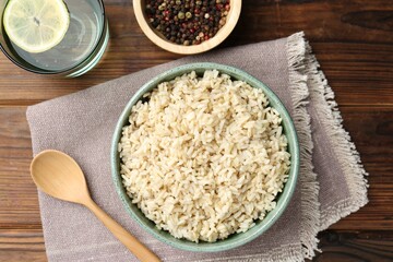 Delicious brown rice served on wooden table, flat lay
