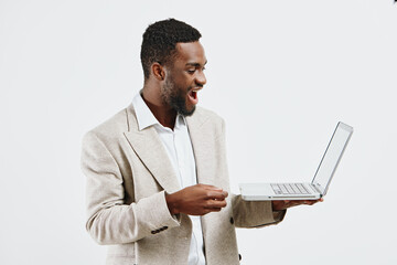 Smiling happy young African American man in business casual attire holding a laptop, looking excited and engaged, isolated on plain white background. Concept: technology, communication, success, work