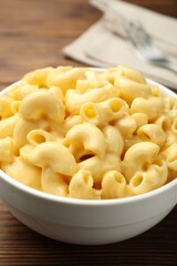 Delicious macaroni and cheese served on wooden table, closeup