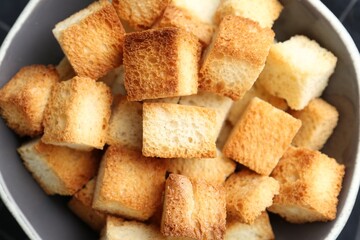Tasty crispy croutons in bowl, top view