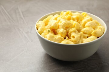Delicious pasta with cheese sauce in bowl on grey table, closeup. Space for text