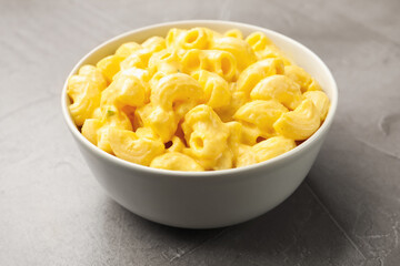 Delicious pasta with cheese sauce in bowl on grey table, closeup