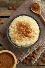 Delicious rice pudding with cinnamon and almonds on wooden table, flat lay
