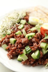 Delicious salad with brown rice on white table, closeup