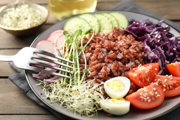 Tasty salad with brown rice served on wooden table, closeup
