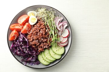 Tasty salad with brown rice on white wooden table, top view