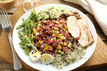 Tasty salad with brown rice served on wooden table, closeup