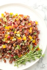 Tasty salad with brown rice on white marble table, top view
