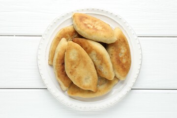 Delicious fried pyrizhky (stuffed pies) on white wooden table, top view