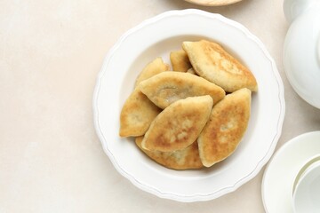 Delicious fried pyrizhky (stuffed pies) on beige table, flat lay. Space for text