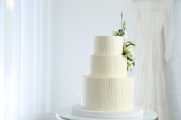 Delicious wedding cake with floral decor on table indoors, space for text