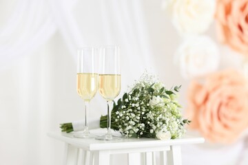 Glasses of champagne and wedding bouquet on table indoors